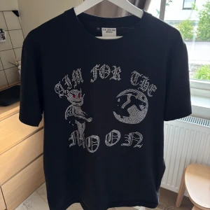 Aim For The Moon t-shirt  - Svart t-shirt från Aim For The Moon i bomull med kort ärm. Framsidan har ett coolt tryck.  Skön passform och perfekt för dig som vill sticka ut !