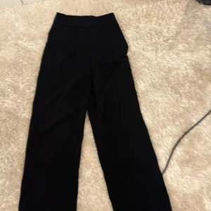 Svarta vida byxor med hög midja kostymbyxor  - Snygga svarta byxor med hög midja och raka, vida ben. Perfekta för en clean och stilren look. Byxorna har en enkel design utan synliga detaljer och passar till många olika outfits.