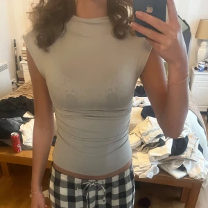 Beige/grå topp från Missäy - Säljer en ljusgrå croppad topp från Missäy med tight passform och rynkade sidor. Toppen är ärmlös och har en enkel, stilren design som passar perfekt till många outfits. Aldrig använd, 130 + frakt