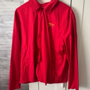 Röd vindjacka från Double A by Wood Wood - Tunn vindjacka från Double A by Wood Wood. Endast använd en gång. Finns risk att den färgar av sig på ljusa färger!!