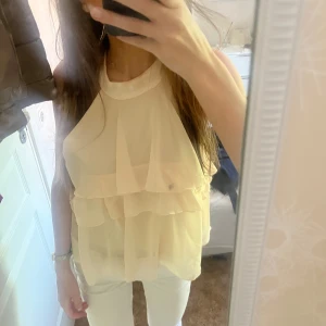 Beige volangtopp med halterneck - Säljer en beige ärmlös topp med halterneck och flera lager volanger. Jättefin nu till sommaren🩷