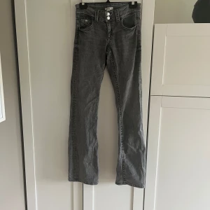 Grå jeansbyxor från Gina Tricot - Säljer ett par grå jeansbyxor från Gina Tricot med raka ben och hög midja. Byxorna har klassisk femficksdesign och stängs med två knappar och dragkedja. Perfekta för dig som gillar en enkel och stilren look.