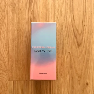 California Dream Eau de Parfum från Louis Vuitton - Louis Vuitton California Dream Eau de Parfum i en snygg förpackning med blå och rosa gradient. Lyxig parfym med elegant design och tydlig Louis Vuitton-logga på toppen av kartongen. Perfekt för dig som gillar exklusiva dofter.