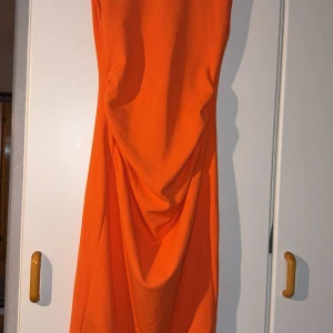 Orange långklänning med v-ringning från Zara - Säljer en snygg orange långklänning aldrig använt med djup v-ringning på baksidan. 