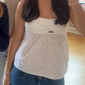 Vit axelbandslös klänning med broderade blommor - Söt vit axelbandslös klänning med omlott-detalj upptill och broderade blommor i tyget från Gina tricot. Perfekt för sommarens alla tillfällen. Klänningen har en romantisk känsla och är lätt att matcha med accessoarer.