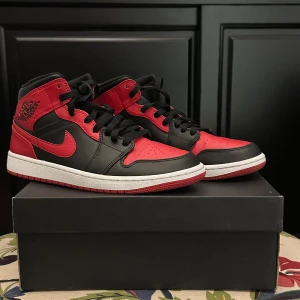 Nike Air Jordan 1  - Säljer ett par Nike Air Jordan 1 Mid i svart och rött med klassisk vit sula.  Har använt dem i en dag tycke inte de va bekväma och ha haft dem på hyllan i ett halv år tänkte de kanske nån annan som gillar de lite mer en mig dem är i väldigt bra skick nästan som nya. De är storlek 42.5.             Om ni har andra frågor de ba ställa.  ingen garanti eller ångerrätt. kan mötas upp i Stockholm/årsta  eller skickas. Pris är inte skrivet i sten 