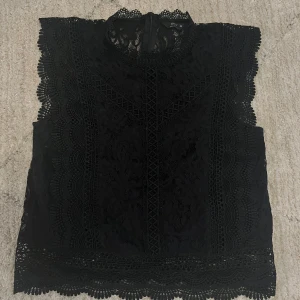Svart spetsblus från ONLY - Supersnygg svart blus från ONLY i spets med vackra detaljer och mönster. Blusen är ärmlös och har en hög hals med dragkedja i ryggen. Perfekt för att lyfta vilken outfit som helst! Pris kan såklart diskuteras samt övriga frågor💕