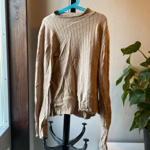 Beige ribbad långärmad tröja - Säljer en beige långärmad tröja med ribbad struktur och rund hals. Tröjan har en enkel och stilren design som passar perfekt till vardags. Materialet känns mjukt och bekvämt mot huden.