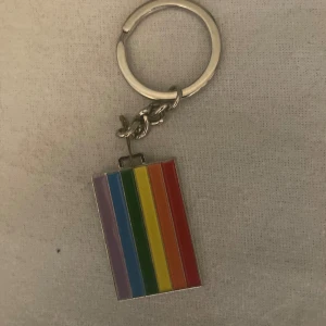 Nyckelring, Prideflagga - Säljer en snygg nyckelring med en regnbågsflagga/peodeflagga. Perfekt accessoar för att visa din pride eller bara addera lite färg till dina nycklar. Metallring och färgglad emalj.