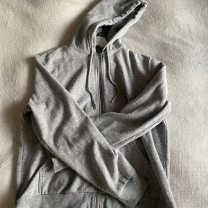 Grå hoodie med dragkedja  - Säljer en klassisk grå hoodie från H&M med dragkedja. Storleken är M men den skulle nog passa S också. Den har använts få gånger och är super bra skick. 