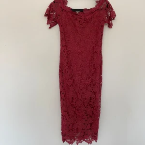 Vila röd klänning, storlek S, helt ny med prislapp - Elegant, röd klänning med spetsdetaljer och en figurnära passform. Perfekt för festliga tillfällen. Strl S Helt ny med prislapp