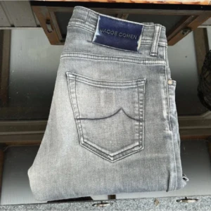 Jacob cohen jeans - Nu har vi fått in ett par galet feta cohen jeans som är i en sjukt snygg tvätt med en galet snygg cohen lapp där bak i navyblå! Verkligen galet snygga. Kvaliten är grym på dessa cohen jeans! Size 31! Modell: Bard. Skick 8/10! Hör av dig vid minsta lilla fundering!! Mått: midja= 41cm. Längd 104cm! 