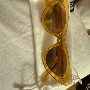 Gula solglasögon från Chimi - Snygga solglasögon från Chimi i en genomskinlig gul färg med markerad båge och mörka glas. Modellen har en trendig, något kantig form och levereras med originalfodral och putsduk.