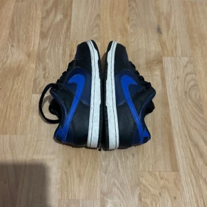 Nike Dunk sneakers i svart och blå - Trendiga Nike Dunks i barn storlek 31. Suveränt skick med mycket få tecken på användning. 