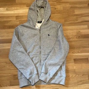 Ralph Lauren zip hoodie - Tja! Säljer en grå Ralph lauren hoodie, skick 10/10 då den är helt ny. Den är i storlek L. Skriv vid frågor/funderingar!