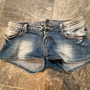 Blå jeansshorts  - Snygga blå jeansshorts med slitna detaljer och klassisk femficksdesign. Shortsen har låg midja, knapp- och dragkedjestängning samt råa kanter nedtill för en avslappnad look. Perfekta för varma dagar. Så fina men tyvärr för stora!