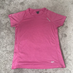 Rosa träningst-shirt från Karhu - Sportig rosa t-shirt från Karhu i funktionsmaterial. Perfekt för träning med korta ärmar och rund halsringning. Liten logga på bröstet och vid nederkanten. Sval och bekväm passform.