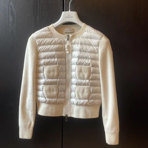 Vit moncler cardigan  - Säljer min super snygga cardigan för jag inte tycker att den passade mig så bra😊 den är tvättad i tvättmaskin en gång så den är inte smutsig alls men den ser lite använd ut❤️ storlek xs och finns galje och påse till☺️ skriv privat om det finns fler frågor