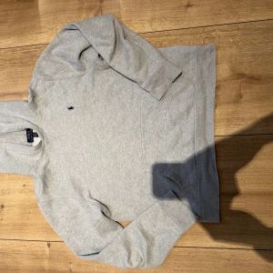 Grå hoodie från Polo Ralph Lauren - Säljer en klassisk grå hoodie från Polo Ralph Lauren i storlek S. Passar 160-170cm. Tröjan har en broderad logga på bröstet, huva och en stor magficka. Perfekt för en avslappnad och stilren look. 