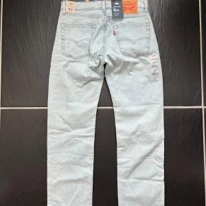 Ljusblå Levi's 505 jeansbyxor - Säljer ett par helt nya klassiska ljusblå Levi's 505 jeans med regular straight passform. Byxorna har fem fickor, orangea sömmar och Levi's ikoniska läderpatch bak. Perfekta till sommaren! 