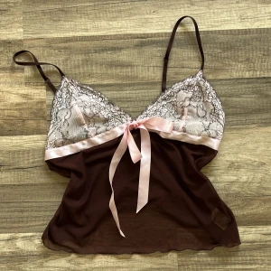 Brun och rosa spetslinne från La Senza - Säljer ett brunt linne från La Senza med tunna axelband, spets upptill och ett satinband framtill som kan kan knyta. väldigt coquette och söt, storlek S/M för stor för mig som brukar ha XS/S. Det står storlek 40 men det är den verkligen inte. Det bruna är ganska genomskinligt men det är inte det rosa.