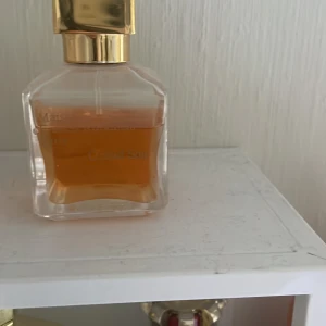 Grand soir  - Elegant parfymflaska från Maison Francis Kurkdjian med fyrkantig form och guldigt lock. Flaskan är genomskinlig och innehåller en bärnstensfärgad vätska. Perfekt för dig som gillar lyxiga dofter och snygg design.