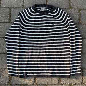 Randig stickad tröja från Morris - Säljer en svart och vit randig stickad tröja från Morris. Tröjan har lång ärm, rund halsringning och ribbad struktur. Klassisk och stilren design med Morris-logga broderad på bröstet.