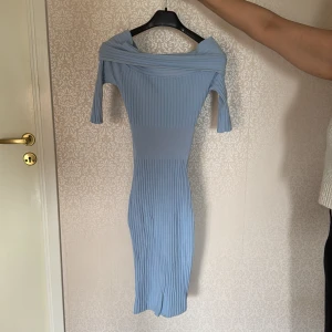 Ljusblå ribbad offshoulder klänning - Säljer en ljusblå ribbad klänning med offshoulder-design och lång ärm. Klänningen är figurnära och har en snygg struktur. Använd en gång! 💕