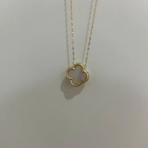 Guldigt halsband med fyrklöver-hänge - Säljer ett elegant halsband i guld med ett öppet fyrklöverformat hänge. Kedjan är tunn men har små detaljer längs kanterna. Fick den i present så har aldrig använt den.
