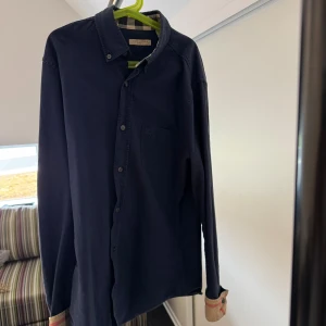 Mörkblå skjorta från Burberry - Säljer en sjukt snygg och stilren mörkblå skjorta från Burberry. Skicket är 9/10 då den är sparsamt använd. Storlek S. passar perfekt nu till sommaren