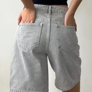 Gråa jeansshorts med raka ben - Säljer ett par gråa jeansshorts med raka ben och klassiska fem fickor. Shortsen har bälteshällor, knapp och dragkedja framtill samt två bakfickor. Perfekta för en avslappnad stil.