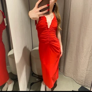 Röd omlottklänning med rynkade detaljer - Säljer en snygg röd klänning med v-ringning och rynkade detaljer framtill. Perfekt för sommaren🥰