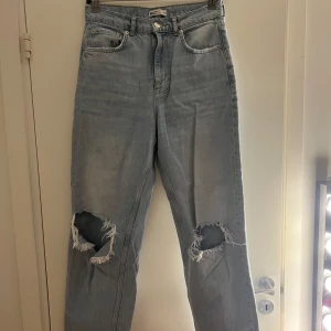 Ljusblå slitna jeans från Perfect Jeans - Ljusblå jeans med hög midja från Perfect Jeans. Modellen har raka ben och stora slitningar vid båda knäna för en trendig look. Klassisk femficksdesign och knappgylf. Perfekta för en avslappnad stil.
