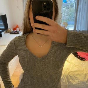 Grå ribbad långärmad tröja - Säljer en grå ribbad tröja med v-ringning och långa ärmar. Tröjan har en tight passform och är perfekt för lager-på-lager. Enkel och stilren design som passar till det mesta. Jätte fin från bikbok