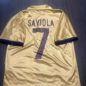 Guldig saviola tröja i barcelona nr7 - Säljer min helt sjukt snygga Saviola tröja i guldfärg i barcelona nr7! Tröjan är i storlek 164 fast mindre i storleken! Det ända som drar ner priset är det mycket dåliga skicket! Den är nopprig över hela tröjan men pågrund av att den är väldigt gammal! Hör av dig vid minsta lilla fundering och kolla gärna in mina andra artiklar på min profil!  Fotboll fotbollströja fotbollsskor Nike Barcelona T-shirt grisch thiago alcantara Adidas football shirt saviola guld