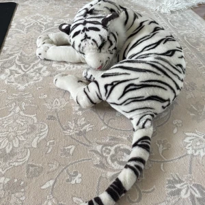 Vit tiger gosedjur - Stor vit tiger gosedjur med svarta ränder och rosa nos. Mjuk och fluffig, perfekt som prydnad eller kramkompis. Längden är cirka 70cm. Maskintvätt i 30g 