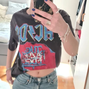 Svart AC/DC t-shirt med tryck - Cool svart t-shirt med stort AC/DC-tryck framtill. T-shirten har korta ärmar och en avslappnad passform, perfekt för dig som gillar bandtröjor och rockstil. Sälj för använder it längre💕