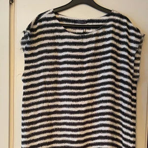 *NY*Svart/vit Randig klänning från Crocker Sthlm, Presenttips i stl L  - Ny oanvänd med prislapp. Ord pris: 599 sek, Pris nu: 50 sek. Kortare klänning/tunika. Mkt tunt och svalt material, ej genomskinlig. Fransig i ärmslutet, vilket tillhör designen/modellen. Passar stl L 40/42. Perfekt för dig som gillar en enkel men stilren look.