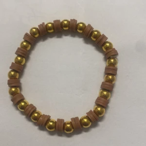 Armband med guldpärlor och bruna detaljer - Snyggt armband med glänsande guldpärlor och bruna detaljer. Perfekt för att ge en touch av stil till din outfit. Elastiskt band för enkel passform.