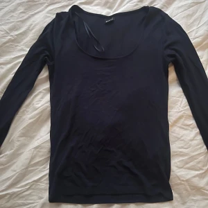 Marinblå långärmad topp från Gina Tricot - En enkel och stilren marinblå långärmad topp från Gina Tricot. Modellen har rundad urringning och är tillverkad i ett mjuk, lent och luftigt bomullsmaterial med ett litet snitt i slutet av armen. Perfekt basplagg att ha i garderoben! 💕