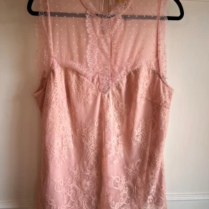 Rosa spetsblus, ny - Säljer en romantisk rosa spetstopp med prickigt mesh-överdrag och vackra spetsdetaljer. 