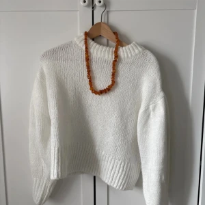 Vit stickad tröja från H&M Divided - Säljer en vit stickad tröja från H&M Divided. Tröjan har en klassisk rund halsringning och långa ärmar med breda ribbade muddar. Perfekt för lager-på-lager och enkel att matcha med olika outfits.