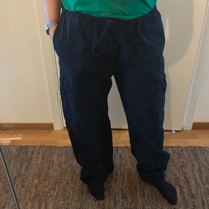 Svarta cargopants från BikBok - Svarta cargopants från BikBok med dragsko i midjan och fickor på sidorna. Byxorna har en loose passform och resår vid bensluten. Perfekta för en avslappnad och trendig stil.