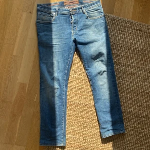 Blå jeans från Jacob Cohën (Uppsydda) - Limiterade Jacob Cohën jeans – nr 046 av 443 👖 Stilrena blå jeans i klassisk femficksdesign med J-detalj på myntfickan, knappar i gylfen och orange patch baktill. Limiterad modell ✂️ Jeansen är uppsydda för att passa dig som är ca 170–175 cm, men funkar även bra för både kortare och längre. ⚠️ Två små svarta fläckar på vänstra bakfickan – ej särskilt synliga. har inte försökt bli av med dem.  💬 Priset är förhandlingsbart! Skriv gärna om du vill ha fler bilder eller har andra frågor!