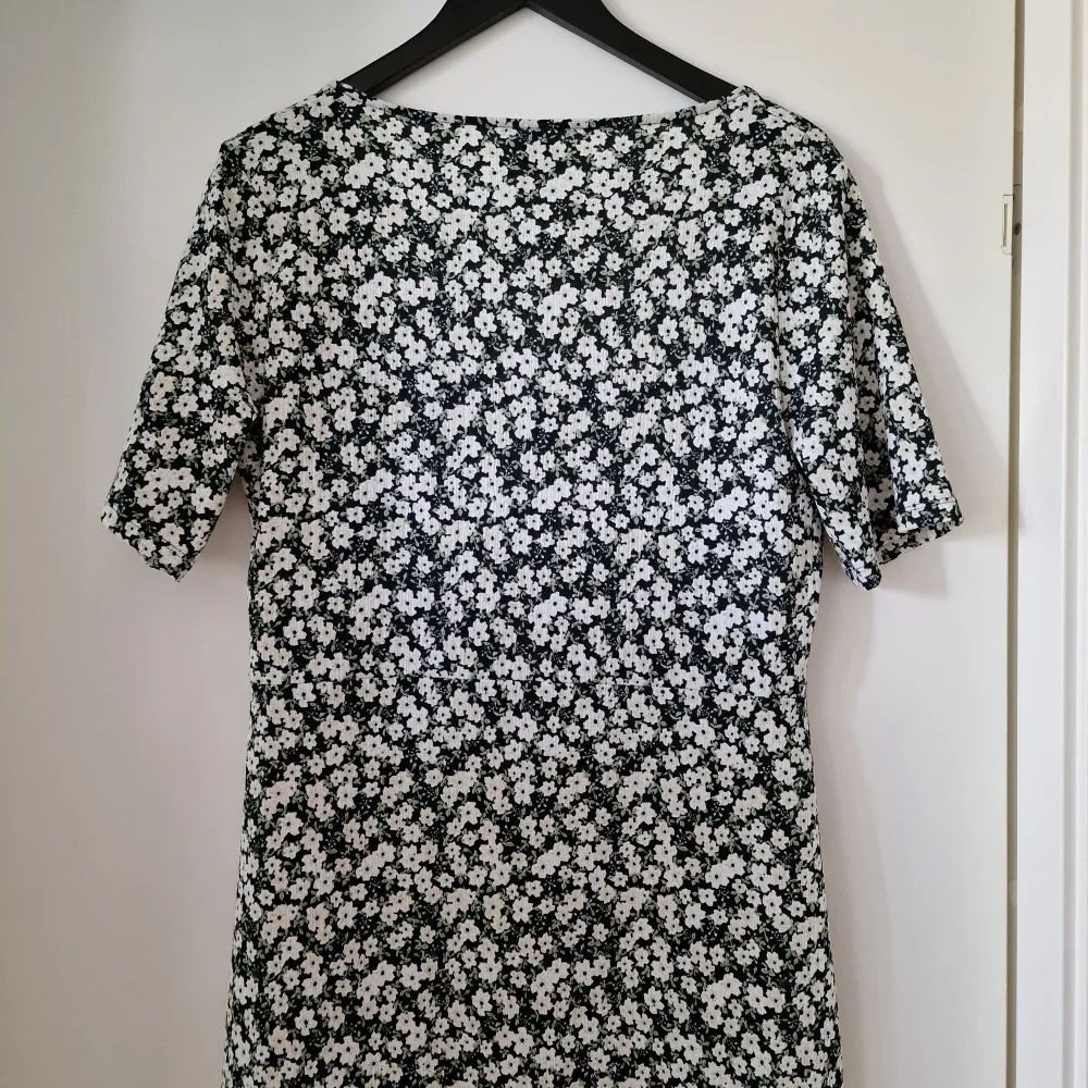 Säljer en snygg blommig klänning från Gina Tricot i storlek XL. Klänningen har en svart bas med vita blommor och korta ärmar. Den är figurnära med en slits på sidan för extra stil. Perfekt för sommarens alla tillfällen! Aldrig använd. Ganska elastisk.. Mekot.