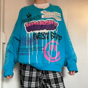Säljer en turkos oversized sweatshirt med stora grafiska tryck i lila, svart, vitt och rosa framtill. Tröjan har långa ärmar och rund halsringning. Från märket unlock7 skapat av Lisa Anckarman. Köpte från Vinted men har inte kommit till användning. Storlek S/M men passar mer L/XL beroende på hur oversized man vill ha. Perfekt för dig som gillar streetplagg😊