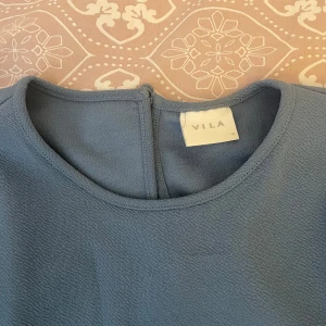 Blå långärmad tröja från Vila - Snygg blå långärmad tröja från Vila. Perfekt för en stilren look med sin enkla design och mjuka material. Passar bra till både jeans. Den är i storlek m 