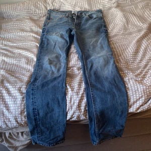 Blå jeans från 157 - Klassiska blå jeans från 157 med fem fickor och normal passform. Jeansen har en läderpatch bak i midjan och stängs med dragkedja och knapp. Perfekta för dig som gillar en tidlös stil.