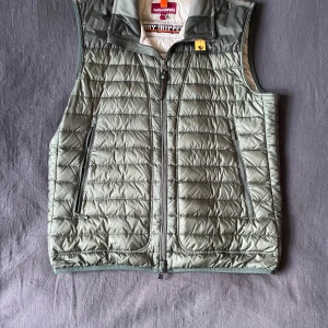 Grön Para Jumpers väst.  - Säljer en snygg grön quiltad väst från Parajumpers. Västen är mörk/oliv grön, storlek L och av modellen Day tripper. Västen är i väldigt bra skick och använd sparsamt. Autentisering genom certilogo funkar bra. Nypris 3500kr. Skriv gärna vid frågor eller funderingar. 