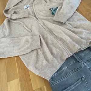 Beige hoodie från Bvaldi - Säljer en snygg beige hoodie från Bvaldi med dragkedja och huva. Tröjan har långa ärmar och ribbade muddar. Perfekt för en avslappnad stil. 🧥